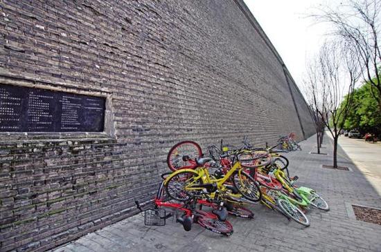 西安乱堆放在城墙边的共享单车。三秦都市报图